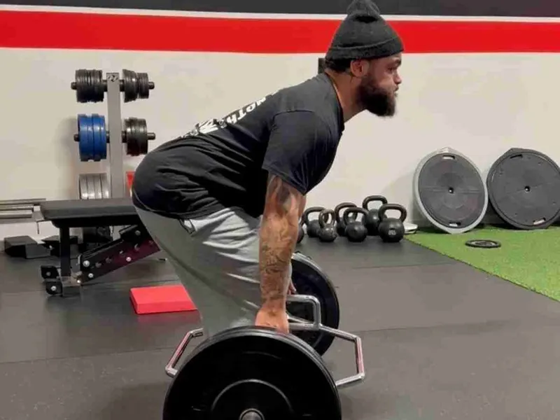 An adult performs a barbell deadlift during strength and mobility training at Rewire Health & Performance