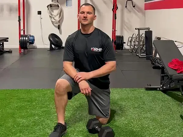 An adult performs a dumbbell lunge on the turf, building everyday strength at RHP in Franklin MA